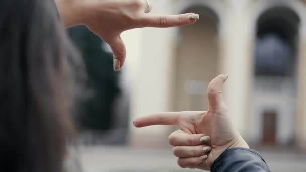 Γυναίκα σκηνοθέτης ελέγχει τη σκηνή για τα γυρίσματα ή με τα δάχτυλά του, κοιτάζοντας μέσα από τα χέρια - Πλάνα, βίντεο