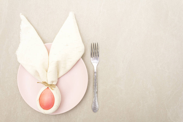 イースターウサギ(ウサギ)卵の概念は、テーブルの配置の装飾。石の背景にプレート、フォーク、布ヴィンテージリネンナプキンピンク(バラ色)の卵、トップビュー - 写真・画像