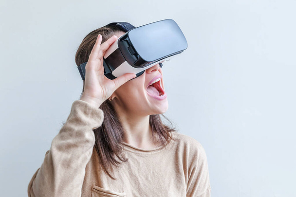 Hymyile nuori nainen yllään käyttäen virtuaalitodellisuus VR lasit kypärä kuulokkeet valkoisella taustalla. Älypuhelin käyttäen virtuaalitodellisuus suojalasit. Teknologia, simulointi, hi-tech, videopeli käsite. - Valokuva, kuva