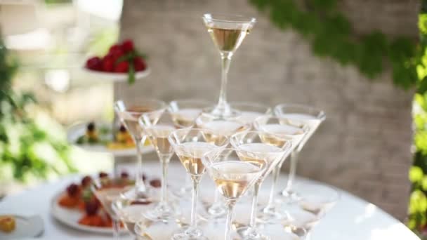 Standing on a table with a pyramid of glasses of champagne - Záběry, video
