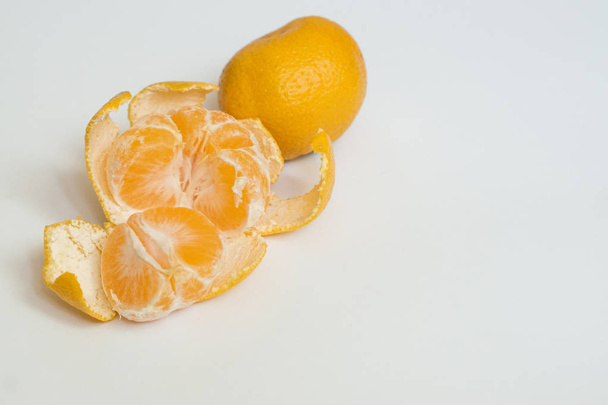 オレンジマンダリン,クレメンティーヌ, 1枚の皮をむいたタンジェリンと白の背景に孤立した葉で半分にカット - 写真・画像