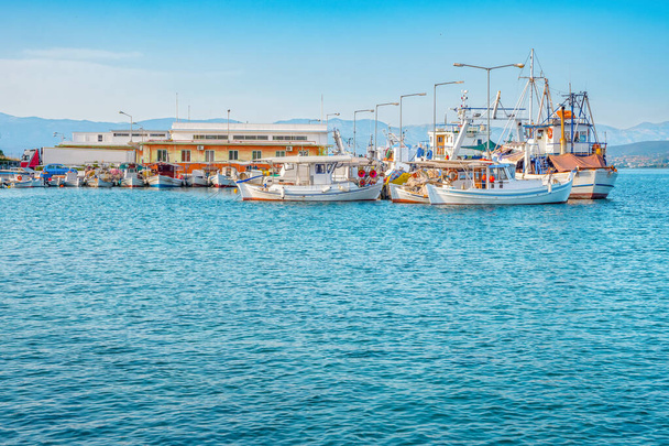 Hodowla ryb Morze Śródziemne. Farma, fabryka ryb Dorada i Sea Bass. Statek zaopatrzeniowy na centralnym rynku rybnym w Euboea, Grecja. Molo rybackie z miastem na horyzoncie - Zdjęcie, obraz