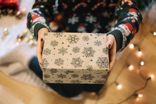 Womans hands holding brown holiday gift box - 写真・画像