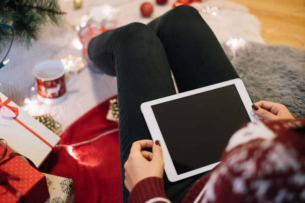 Females legs with tablet next to Christmas tree - Zdjęcie, obraz