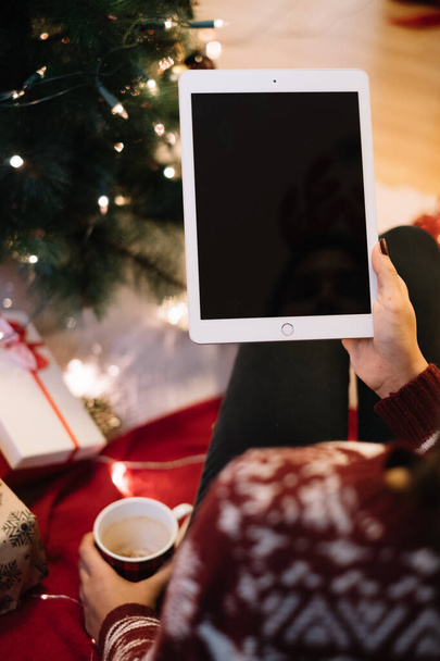 Woman holding tablet near Christmas tree and presents - Foto, Imagen