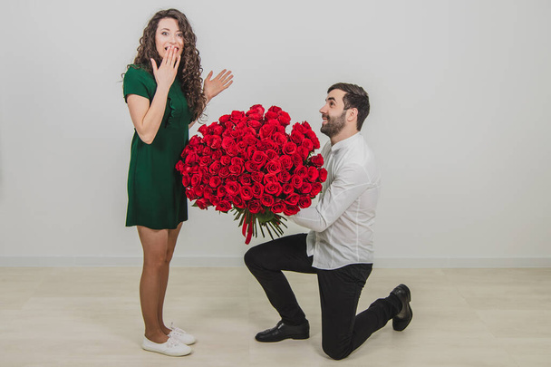 Man asking partner to marry him by giving her a engagement ring and bunch of red flowers, woman is taken aback. - 写真・画像