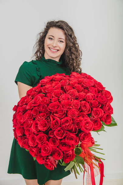 Beautiful young woman with rose bouquet, looking delighted and loved, over white background. - Fotografie, Obrázek
