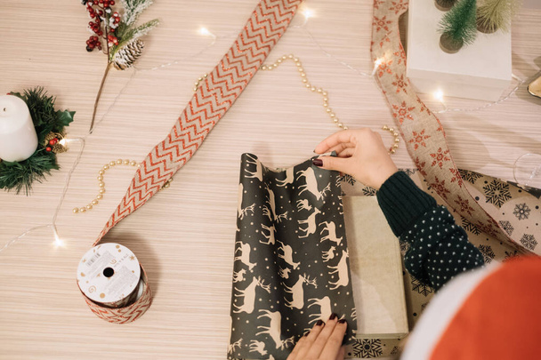 Wrapping Christmas gift on a wooden desk - Valokuva, kuva