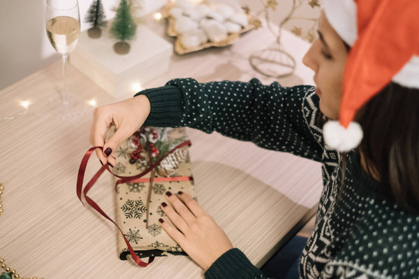 Girl decorating gift with ribbon and pine branch - 写真・画像