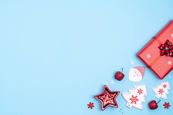 Nieuwjaar en kerst kader. Rode en witte kerstversiering -geschenkdozen, sterren, kerstboom, kerstman op pastelblauwe papieren achtergrond. Bovenaanzicht, flat lay, kopieerruimte - Foto, afbeelding