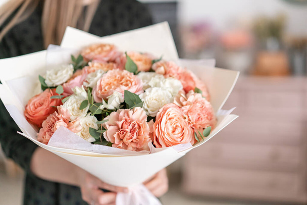 Piękny bukiet mieszanych kwiatów w rękach kobiet. pracy kwiaciarni w kwiaciarni. Ładny, świeży bukiet. Dostawa kwiatów - Zdjęcie, obraz