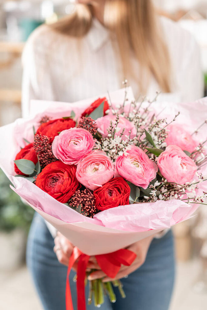 Kadınların elinde güzel bir buket karışık çiçek. Çiçekçi dükkanındaki çiçekçinin işi. Güzel, taze bir buket. Çiçek teslimatı - Fotoğraf, Görsel