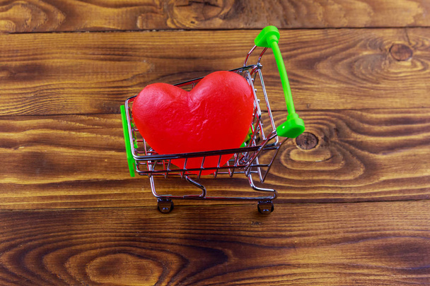 Winkelwagen met groot rood hart op houten achtergrond. Valentijnsdag concept - Foto, afbeelding