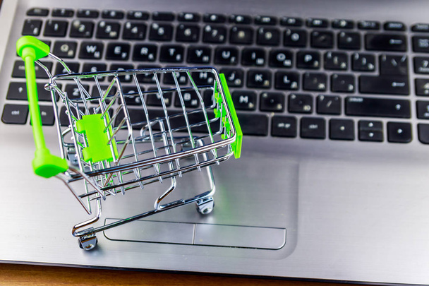 Online Shopping concept. Kleine winkelwagentje op laptop toetsenbord - Foto, afbeelding