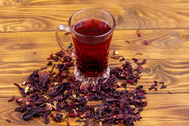 Lasi kuppi punaista hibiscus teetä (carcade, roselle) puupöydällä - Valokuva, kuva