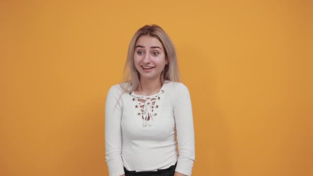 fiatal vonzó nő takaró száj izolált narancs háttér - Felvétel, videó