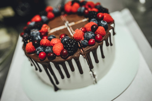 White cake with chocolate glaze and berrys, birthday cake in close up - Fotografie, Obrázek
