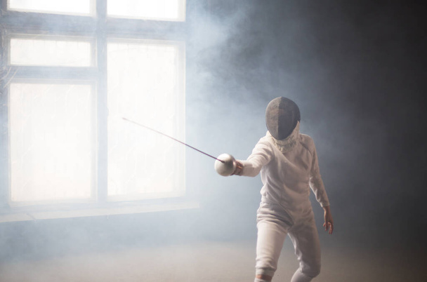 A young woman fencer standing in the attack position - Fotoğraf, Görsel