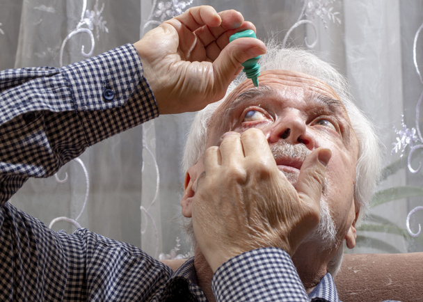 Un homme âgé enterre la médecine dans ses yeux
 - Photo, image