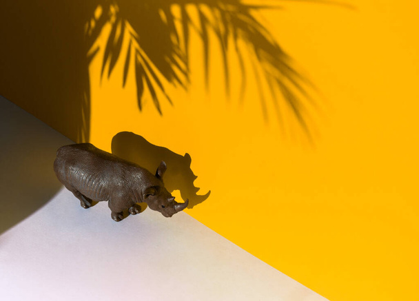 figure of an animal on a yellow background. Shadow of the Plastic Rhino. - Zdjęcie, obraz
