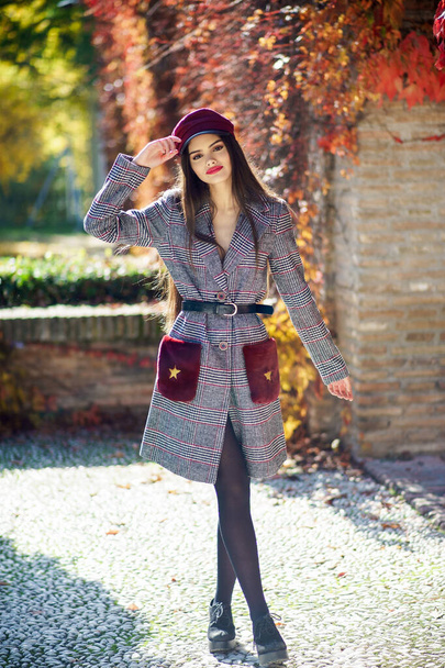 若いです美しい女の子身に着けている冬のコートとキャップで秋の葉の背景. - 写真・画像