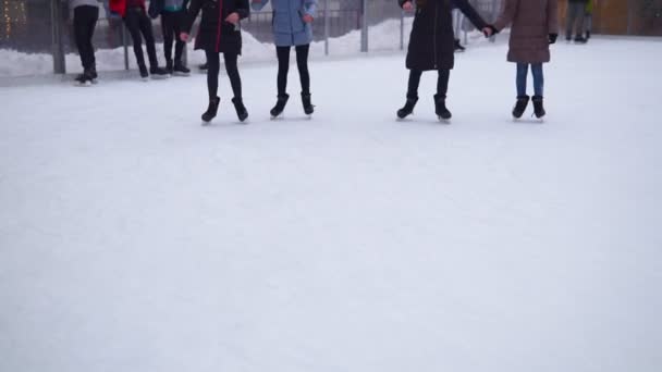Mensen zijn schaatsen op de ijsbaan in de zonnige dag. Veel mensen schaatsen op het ijs op de winter ijsbaan buiten. - Video