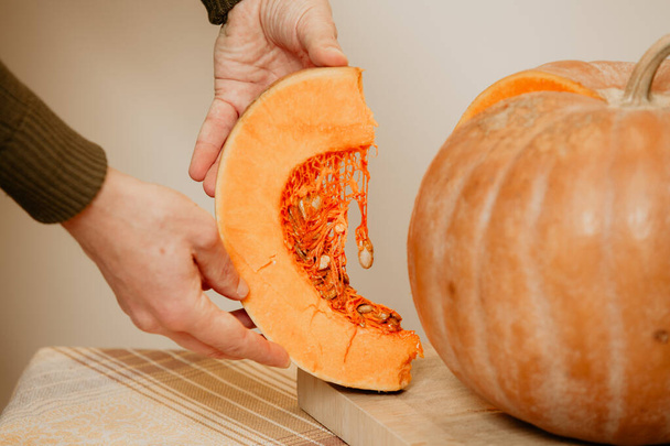 Hands of man holding piece of ripe pumpkin close-up - Foto, imagen