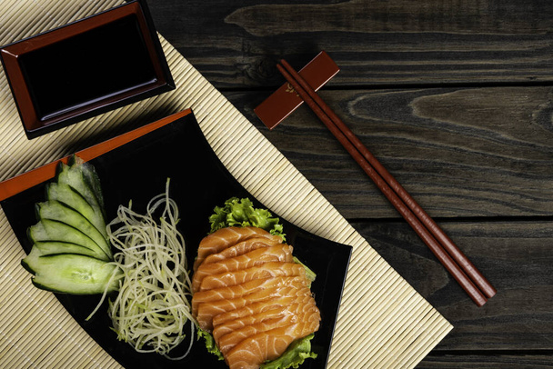 Fresh salmon fish at restaurant very delicious. Japanese foods sashimi on black wood background. - Фото, зображення
