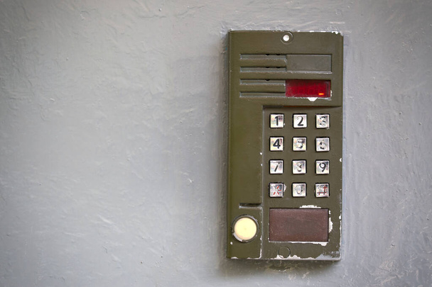 Старый цифровой дверной телефон на серой плоской поверхности
 - Фото, изображение