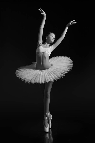 Fiatal lány táncol balettcipőben és tütüben. Fekete-fehér fénykép. - Fotó, kép