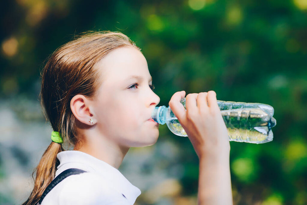 Meisje drinkwater buitenshuis - zeer ondiepe scherptediepte - Foto, afbeelding