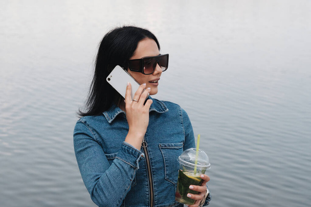 ジーンズで身に着けている1つの美しいブルネットの女の子全体的な用途スマートフォン、通信コンセプト - 写真・画像