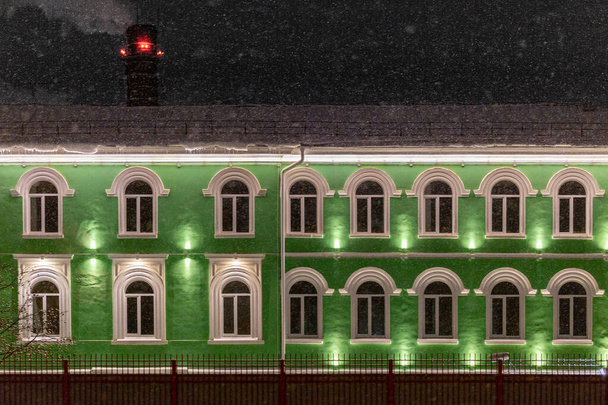 groene huis onder de winter donkere nacht sneeuwval - Foto, afbeelding