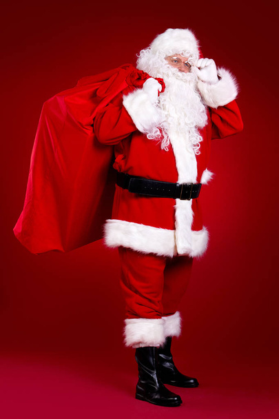 Santa Claus comes with a big bag of gifts. Full length portrait - Фото, изображение