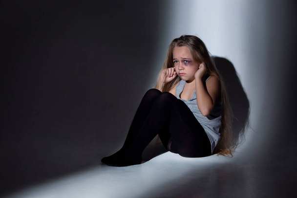 trauriges und verängstigtes kleines Mädchen mit Blutanfall und blauen Augen, das verängstigt sitzt - Foto, Bild