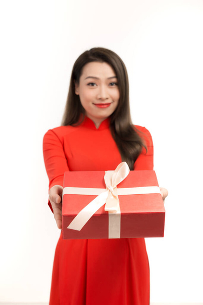 Прекрасна азіатка вдягнена в червоне ао даї, щаслива посмішка тримає новий рік подарункової коробки, ізольований на білому фоні - Фото, зображення