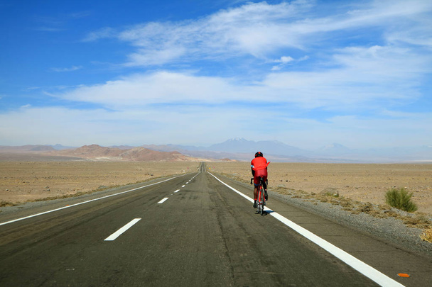 アタカマ砂漠の高地道路をサイクリングする男,チリ北部,南アメリカ - 写真・画像