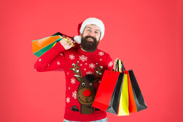 Organized shopper. Compulsive buyer. Retail. Almost christmas. Presents for family. Bearded hipster carry shopping bags. Santa man bought gifts. Christmas gifts. Guy in christmas sweater with deer - Фото, изображение