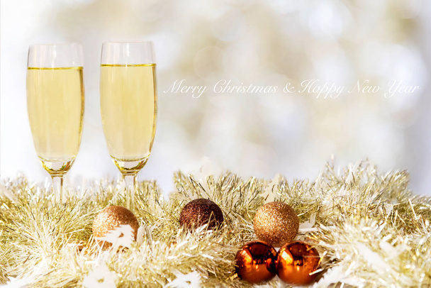 Vrolijk kerstfeest. Champagne in twee glazen vieren en feest Kerstmis thuis. Gele bokhe achtergrond. - Foto, afbeelding