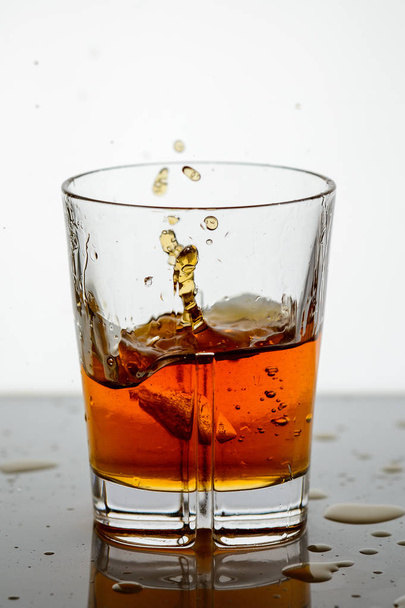 splashing whiskey in a glass on the background14 - Фото, изображение