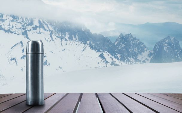 Thermos with tea or coffee and landscape of mountains on background - 写真・画像