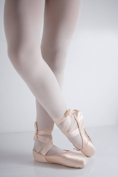 legs and feet with pink satin pointe shoes by a classical dancer - Foto, afbeelding