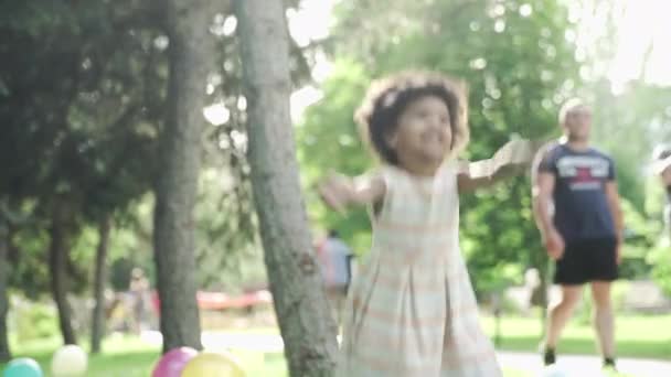 Маленька афро-американська дівчинка грає і стрибає в парк. Невпізнавані люди на фоні
 - Кадри, відео
