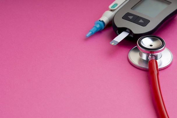 Diabetes-Konzept. Spritze, Glukometer oder Glukosemessgerät und Stethoskop auf rosa Hintergrund. Gesundheitswesen und Medizin  - Foto, Bild