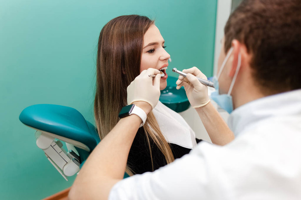 Dentista con un taladro y un espejo está tratando los dientes de un paciente
 - Foto, Imagen