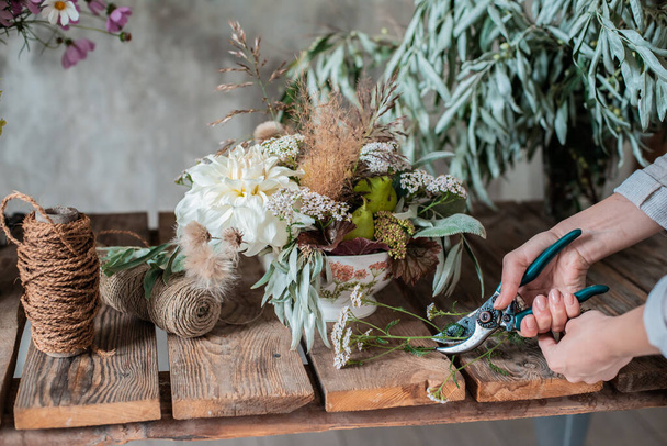 Female professional florist prepares the arrangement of wild flowers. - Photo, Image