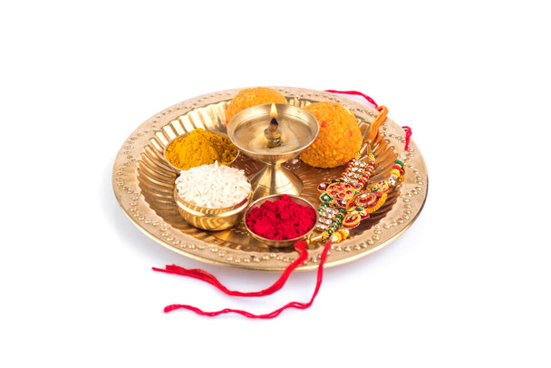 Indian Festival: Rakhi with rice grains, kumkum, sweets and diya on plate with an elegant Rakhi. A traditional Indian wrist band which is a symbol of love between Brothers and Sisters - Zdjęcie, obraz