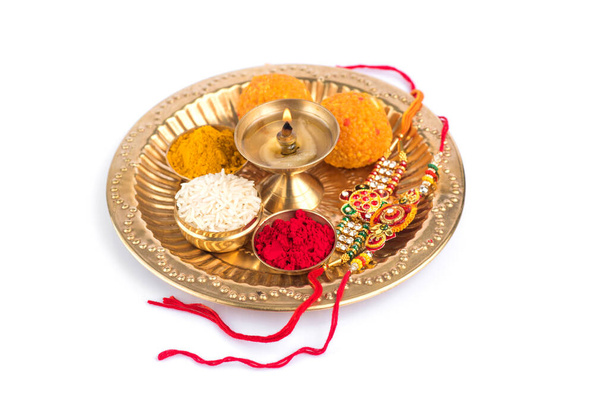 Festival indien : Rakhi aux grains de riz, kumkum, bonbons et diya sur assiette avec un élégant Rakhi. Un bracelet traditionnel indien qui symbolise l'amour entre frères et sœurs - Photo, image