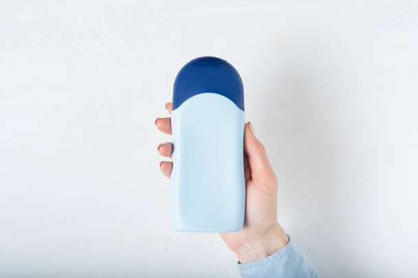 Blue bottle for cosmetic product in a female hand. White background - Photo, Image