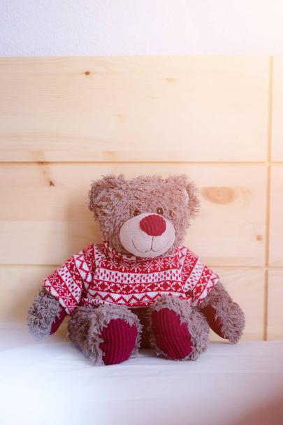 Cute teddy bear toy is sitting in the bed, wakeup at morning, sunlight - Фото, изображение